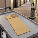 Brauner Papier-Staubsaugerbeutel, schr&auml;g auf einen Reinigungswagen in einem Hotel liegend in Form eines Lifestyle Fotos, im Hintergrund ist ein passender B&uuml;rstsauger.