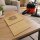 Brauner Papier-Staubsaugerbeutel, schr&auml;g auf einen Tisch in einem Wohnzimmer liegend in Form eines Lifestyle Fotos, im Hintergrund ist ein passender Bodensauger