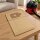Brauner Papier-Staubsaugerbeutel, schr&auml;g auf einen Tisch in einem Wohnzimmer liegend in Form eines Lifestyle Fotos, im Hintergrund ist ein passender kompakter Staubsauger.